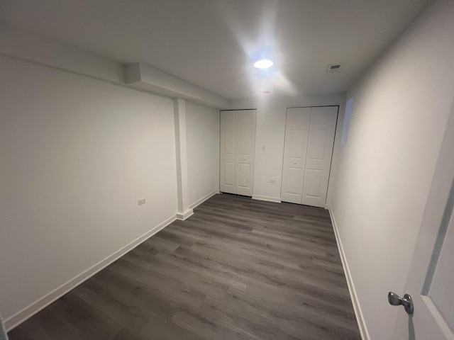 interior space with baseboards, dark wood-style flooring, and two closets