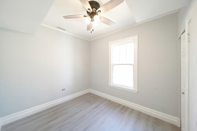 spare room with ceiling fan, wood finished floors, visible vents, baseboards, and ornamental molding