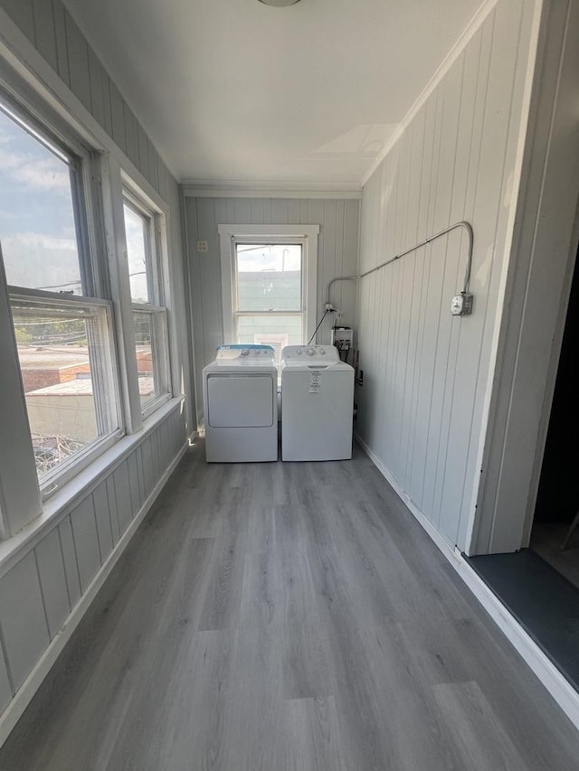 clothes washing area featuring laundry area, plenty of natural light, washing machine and clothes dryer, and wood finished floors