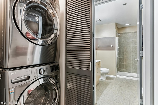 washroom with light tile patterned flooring, laundry area, and stacked washer and dryer