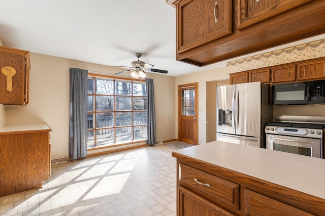 kitchen with appliances with stainless steel finishes, a wealth of natural light, light countertops, and brown cabinets