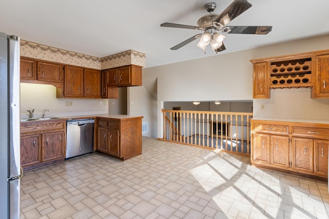 kitchen with ceiling fan, a sink, light countertops, appliances with stainless steel finishes, and brown cabinets