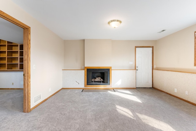 unfurnished living room with carpet, visible vents, a fireplace, and baseboards