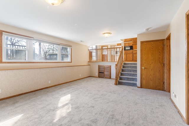 unfurnished living room with stairway, carpet flooring, and baseboards