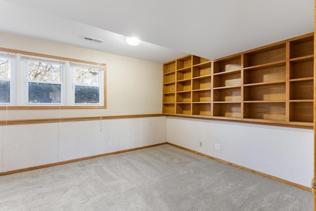 unfurnished room with carpet, visible vents, and baseboards