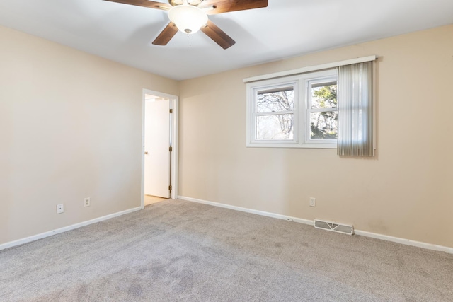 carpeted spare room featuring baseboards, visible vents, and a ceiling fan