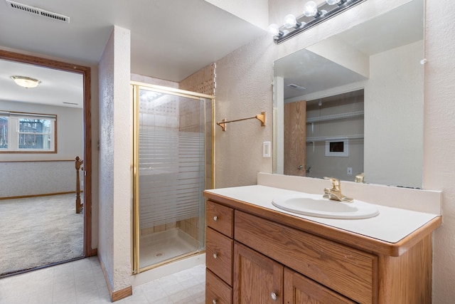 bathroom featuring a textured wall, vanity, visible vents, a shower stall, and tile patterned floors