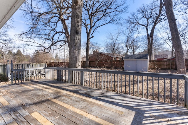 wooden terrace with a storage unit, an outdoor structure, and a fenced backyard