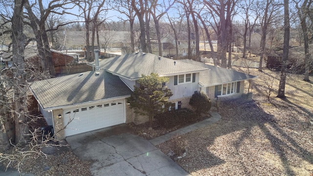 view of front of home with a garage, concrete driveway, brick siding, and roof with shingles