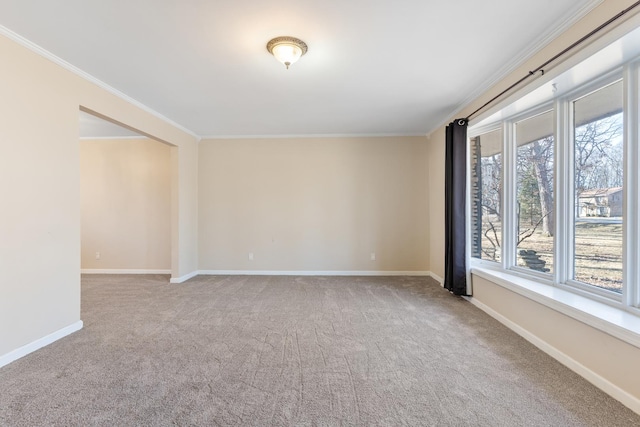 carpeted empty room with ornamental molding and baseboards