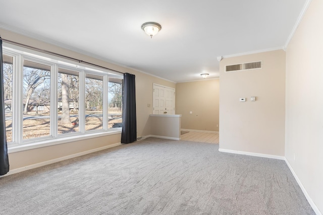 carpeted empty room with ornamental molding, visible vents, and baseboards