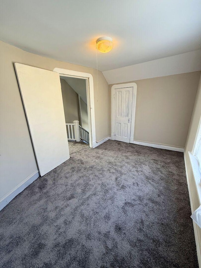 unfurnished bedroom with vaulted ceiling, carpet floors, and baseboards