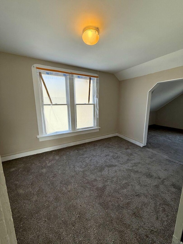 interior space with carpet floors, baseboards, and vaulted ceiling