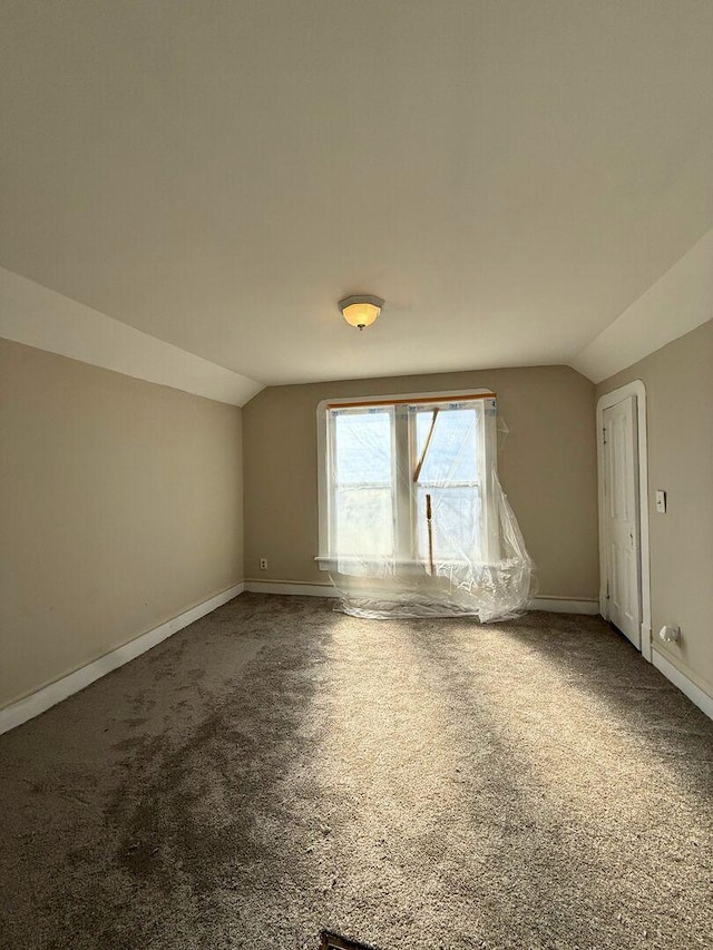 spare room with carpet floors, vaulted ceiling, and baseboards