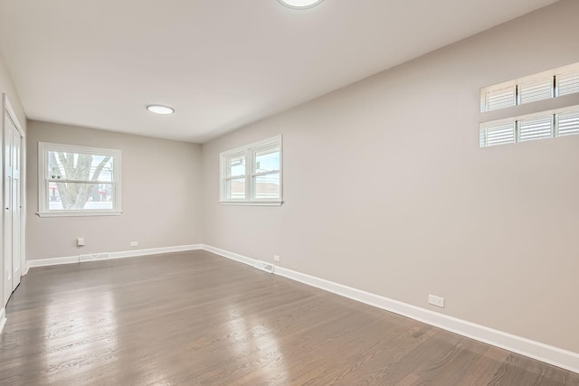 empty room with dark wood-style flooring and baseboards