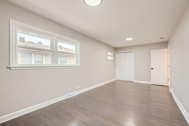 spare room with visible vents, baseboards, and wood finished floors