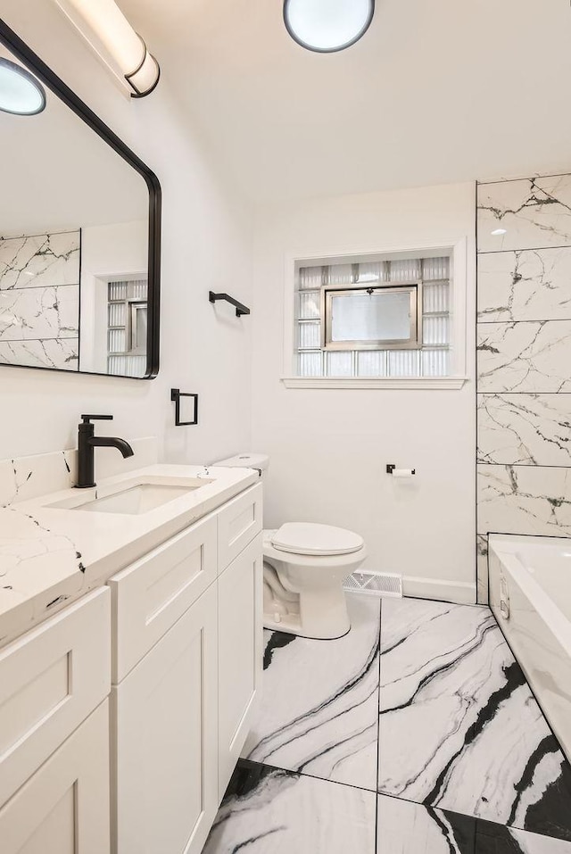 full bath with toilet, marble finish floor, baseboards, and vanity