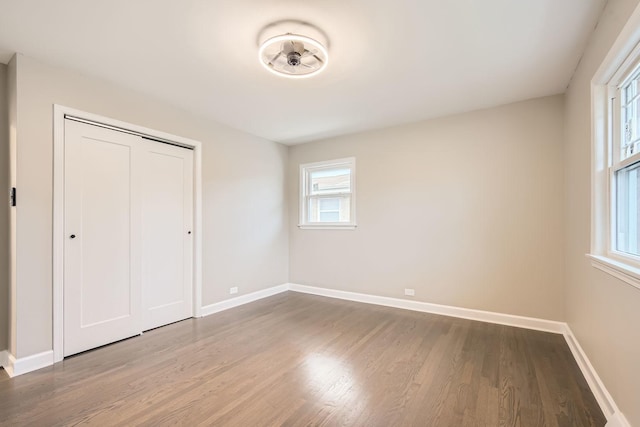 unfurnished bedroom with a closet, baseboards, and wood finished floors