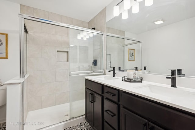 bathroom featuring double vanity, a stall shower, and a sink