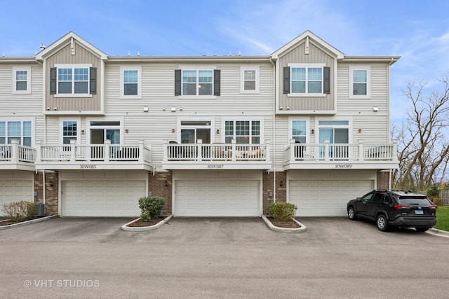 view of front of property featuring brick siding, driveway, central AC, and an attached garage