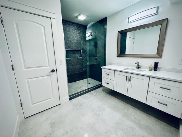 full bath with tiled shower and vanity