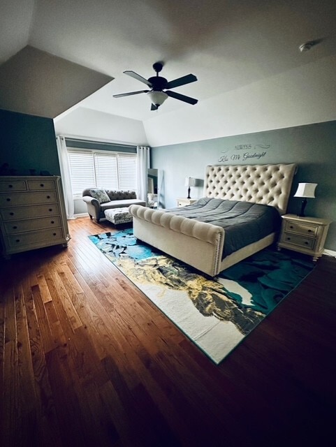 bedroom with a ceiling fan, vaulted ceiling, and hardwood / wood-style floors