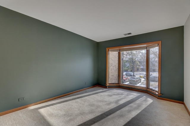 empty room with carpet, visible vents, and baseboards