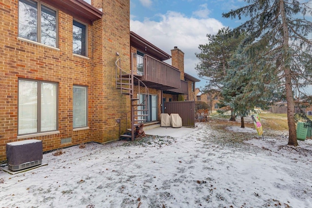 snow covered house with brick siding and a chimney