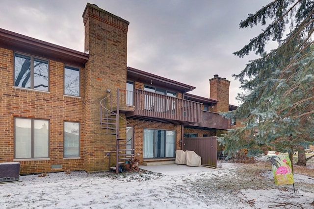 back of house with stairs, a chimney, and brick siding