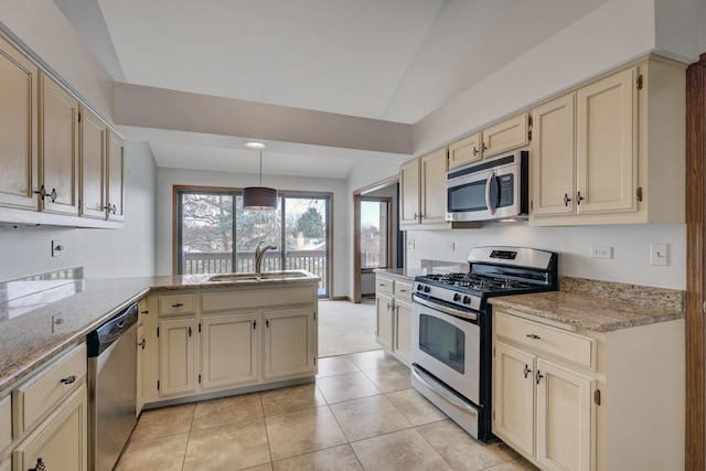 kitchen with a peninsula, appliances with stainless steel finishes, a sink, and cream cabinetry