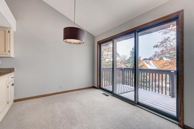 unfurnished dining area with vaulted ceiling, baseboards, visible vents, and light colored carpet