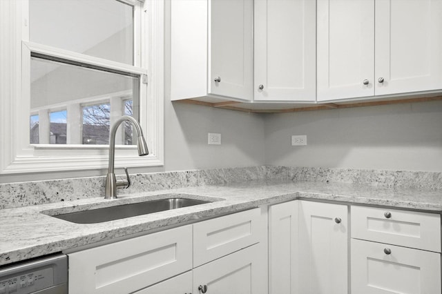 kitchen featuring white cabinetry, dishwasher, a sink, and light stone countertops