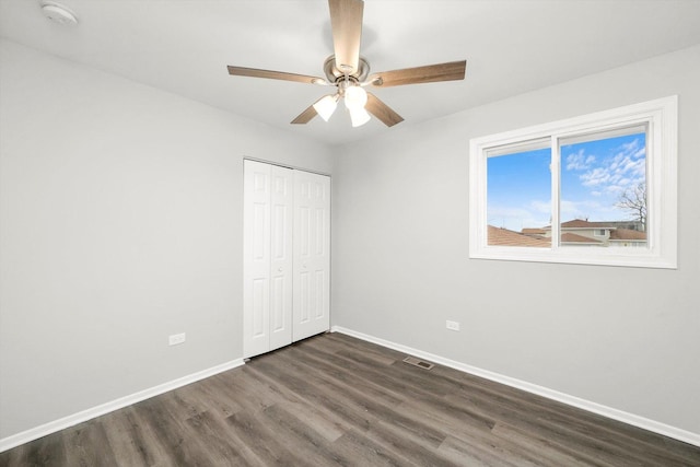 unfurnished bedroom with a closet, visible vents, dark wood-type flooring, a ceiling fan, and baseboards