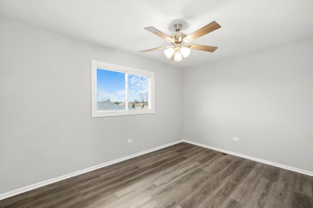 unfurnished room with visible vents, dark wood-type flooring, a ceiling fan, and baseboards