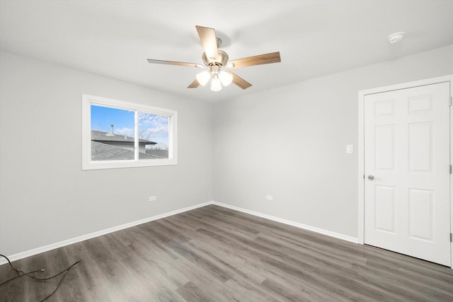 unfurnished room with ceiling fan, baseboards, and wood finished floors