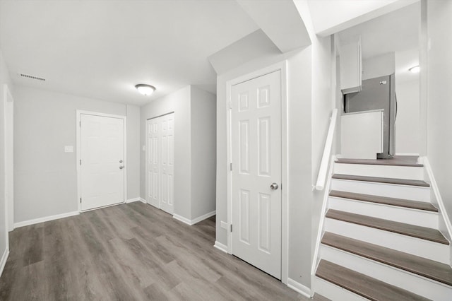 staircase with baseboards, visible vents, and wood finished floors