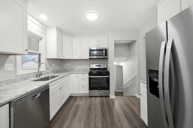 kitchen featuring white cabinets, dark wood finished floors, light stone counters, stainless steel appliances, and a sink