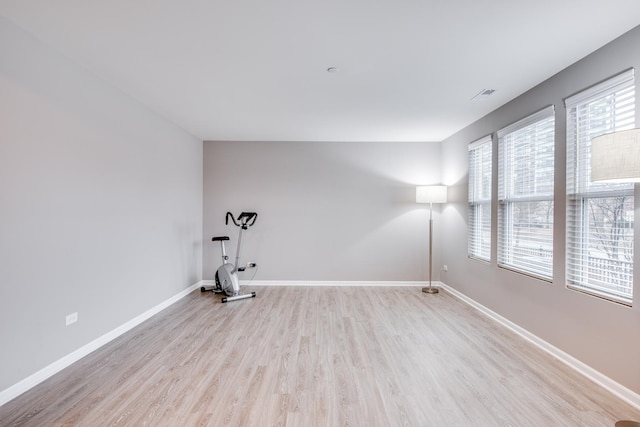 spare room featuring light wood-type flooring, visible vents, and baseboards