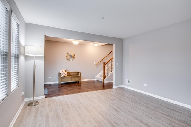 spare room with visible vents, stairway, baseboards, and wood finished floors