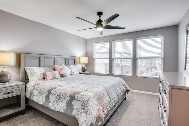 carpeted bedroom with ceiling fan, multiple windows, and baseboards