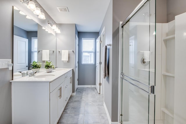 full bathroom with visible vents, a sink, a shower stall, and double vanity