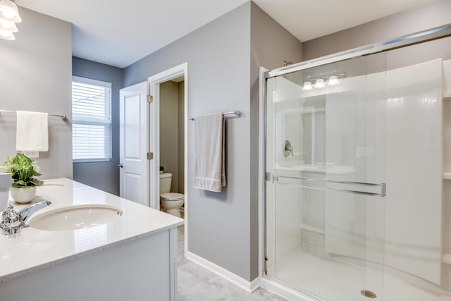 full bath with toilet, a stall shower, baseboards, and vanity