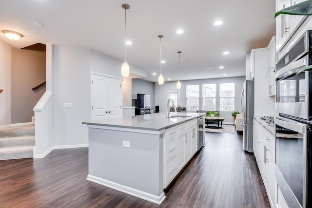 kitchen featuring dark wood-style floors, an island with sink, a sink, and white cabinets