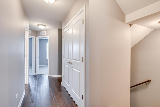 corridor featuring dark wood-style flooring, visible vents, and baseboards