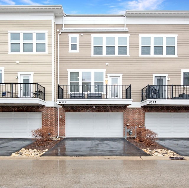 exterior space featuring aphalt driveway, brick siding, and an attached garage