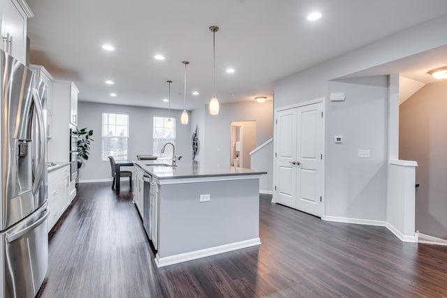 kitchen featuring a kitchen island with sink, stainless steel appliances, a sink, white cabinets, and dark wood finished floors