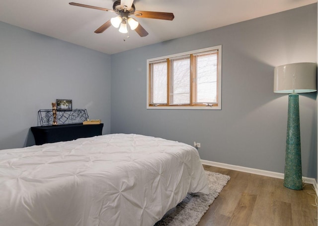 bedroom featuring wood finished floors, a ceiling fan, and baseboards