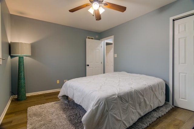 bedroom with a ceiling fan, visible vents, baseboards, and wood finished floors