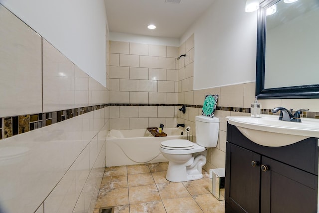 bathroom with tile patterned flooring, toilet, vanity, tile walls, and shower / washtub combination