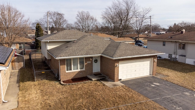 view of front of property featuring an attached garage, brick siding, fence, driveway, and roof with shingles